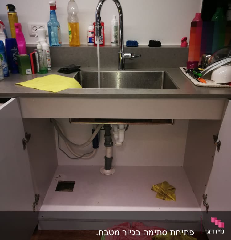 כיור מטבח עם ברז פתוח וצנרת גלויה מתחת